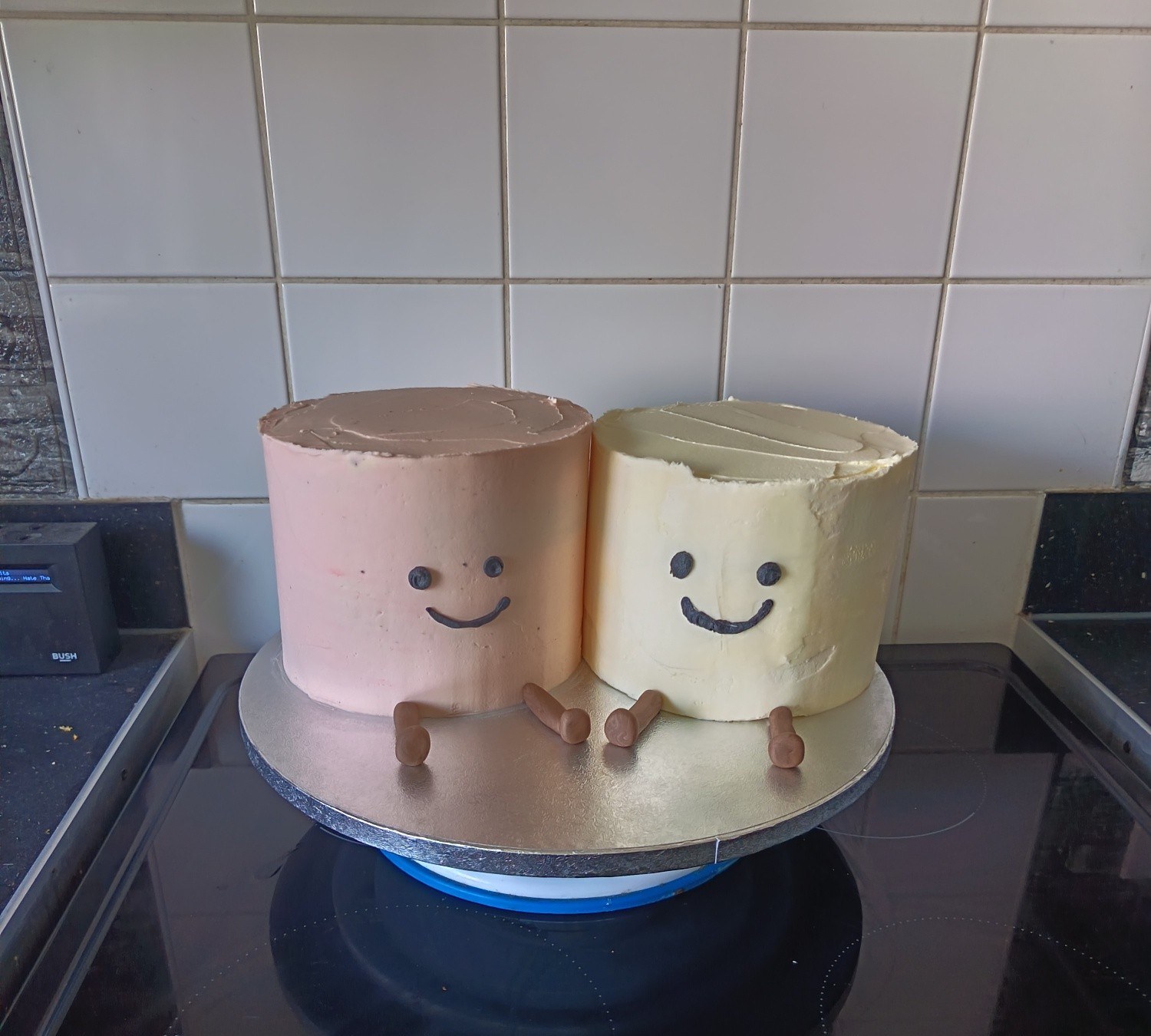 Two cute smiley-faced mini cakes in pink and cream